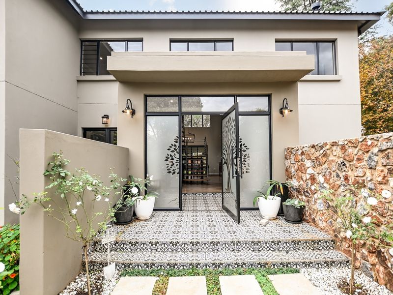 Modern front entrance featuring a decorative glass door, patterned tile steps, and a striking stone feature wall.