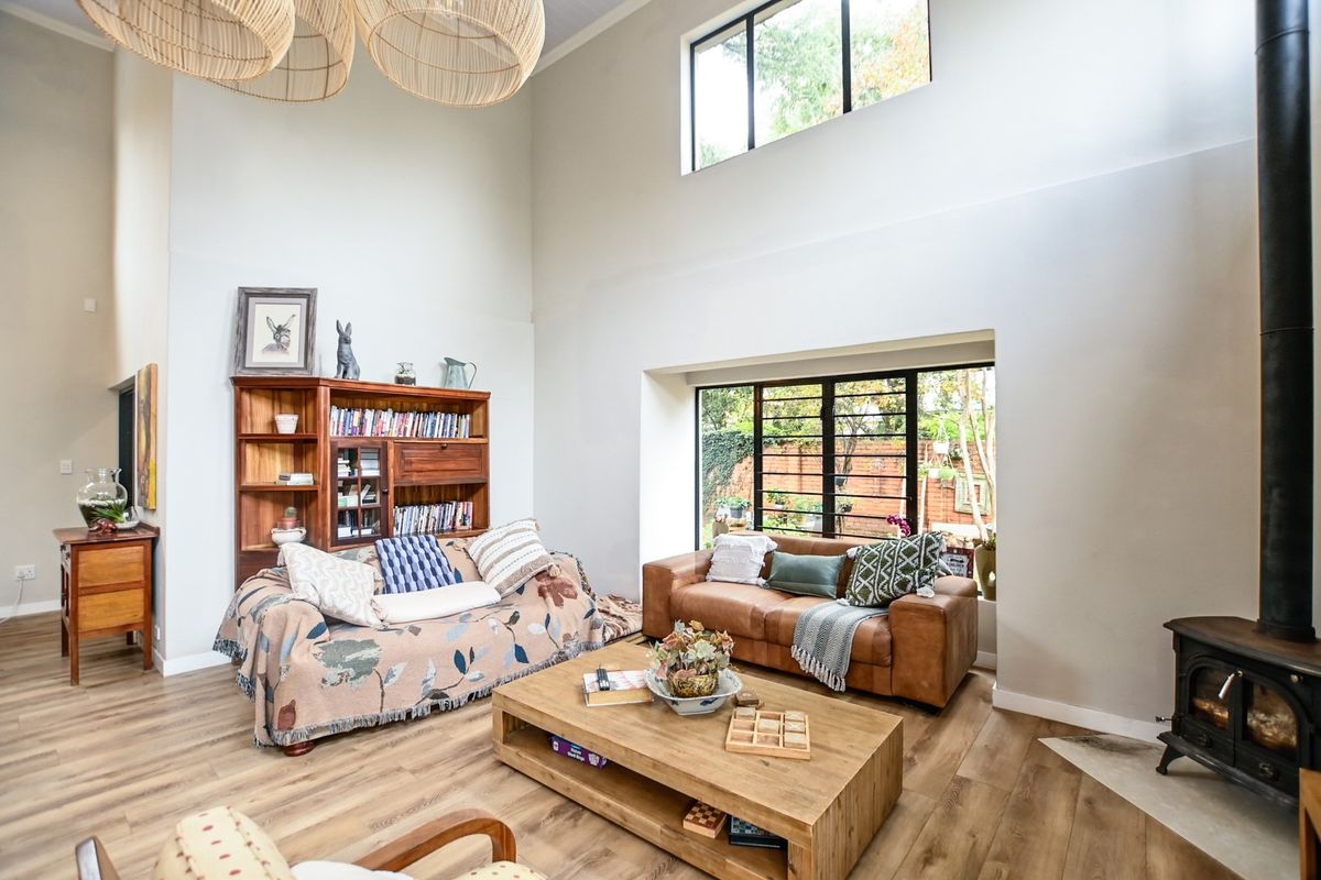 Spacious living room featuring double-height ceilings, a wood-burning stove, and large windows that provide ample natural light and garden views.
