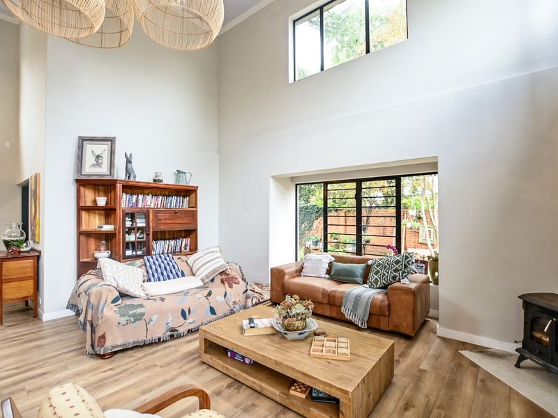 Spacious living room featuring double-height ceilings, a wood-burning stove, and large windows that provide ample natural light and garden views.