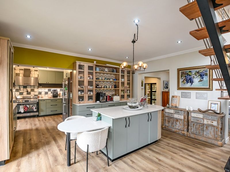 Spacious open-plan kitchen featuring a central island, modern cabinetry, gas stove, and integrated storage, seamlessly connected to the living area and staircase.