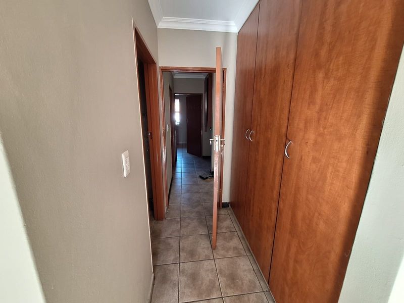 A functional hallway featuring tiled flooring and extensive built-in wooden cupboards, providing ample storage space and connecting multiple areas of the apartment.