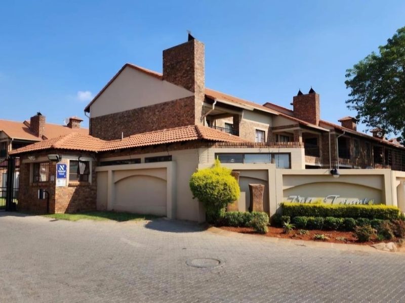 Front elevation of the apartment complex featuring brick construction, tiled roofing, and secure gated entrance access.