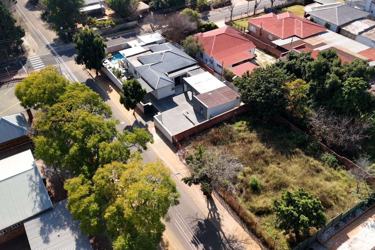 Aerial view of the property showing the main house, swimming pool, driveway, and surrounding residential plot layout.