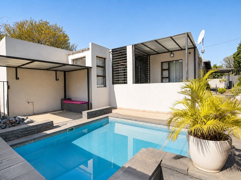 A well-maintained outdoor pool area featuring a swimming pool, stone-clad accents, and a covered patio space, ideal for outdoor relaxation and entertainment.