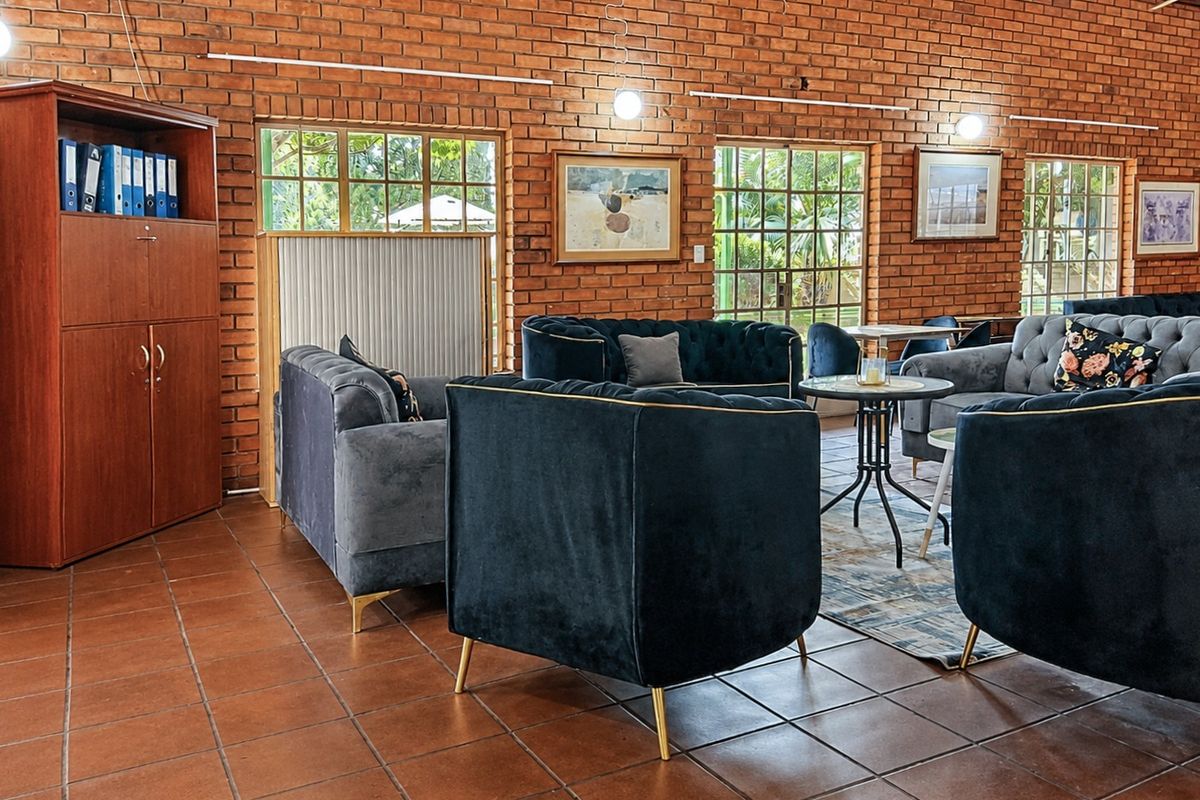 Spacious living area featuring rustic exposed brick walls, terracotta tiled flooring, and large grid-pattern windows providing natural light.