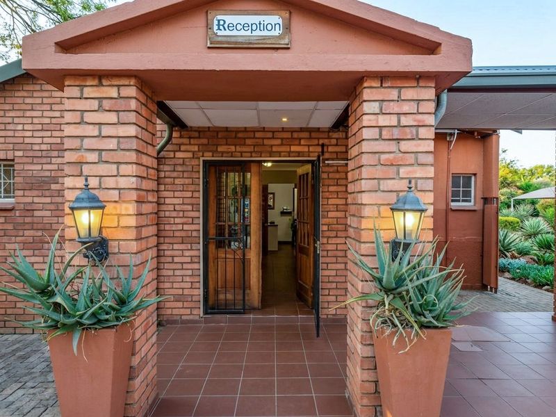 A welcoming front entrance featuring brick pillars, tiled porch flooring, and classic wall-mounted lanterns leading into the reception area.