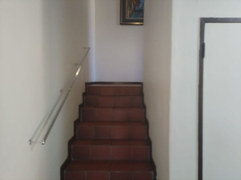 A simple interior staircase featuring tiled steps and a metal handrail, providing access between levels within the townhouse.