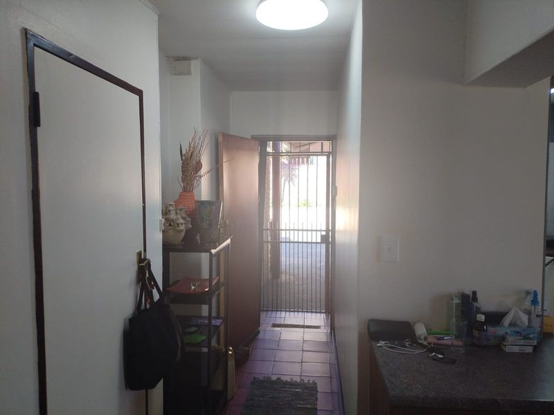 A functional entryway featuring tiled flooring, a secure metal gate, and direct access to the exterior.