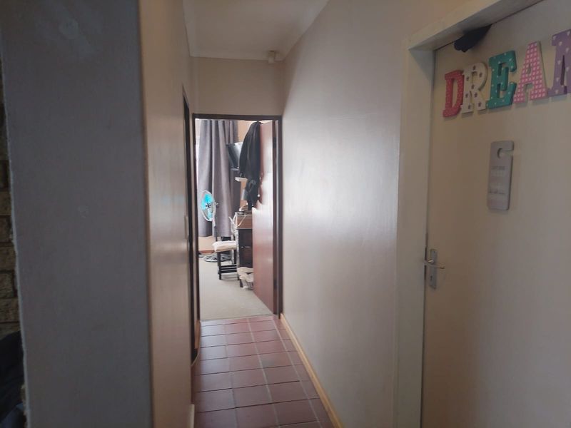 A functional interior hallway featuring tiled flooring and access to adjacent rooms within the townhouse.