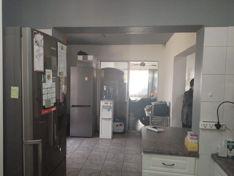 A functional kitchen area featuring tiled flooring, laminate countertops, and built-in cabinetry, with a sliding door leading to an adjacent living space.