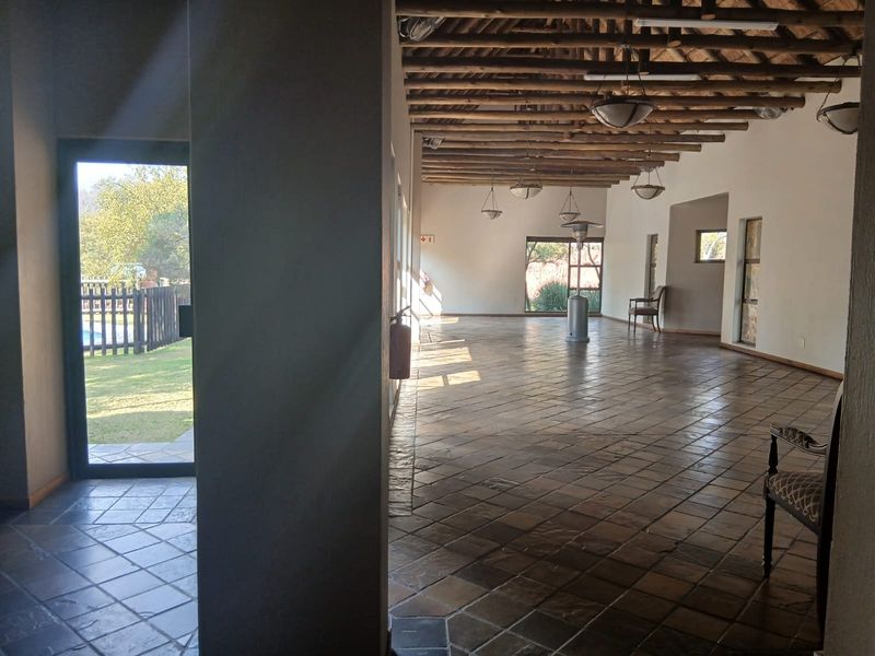 Spacious open-plan living area featuring rustic exposed timber beam ceilings, tiled flooring, and abundant natural light with direct access to the outdoor garden area.