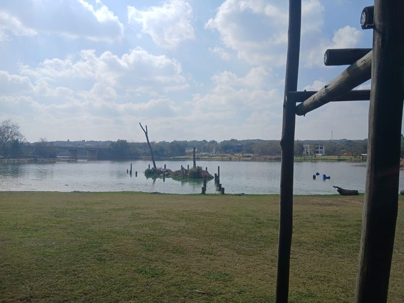 A scenic view of a tranquil lake with a grassy foreground, showcasing the natural landscape and waterfront setting of the property.