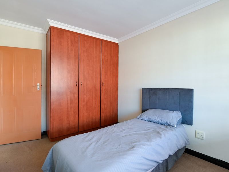 A bedroom featuring neutral walls, carpet flooring, decorative coving, and a large built-in wooden wardrobe.