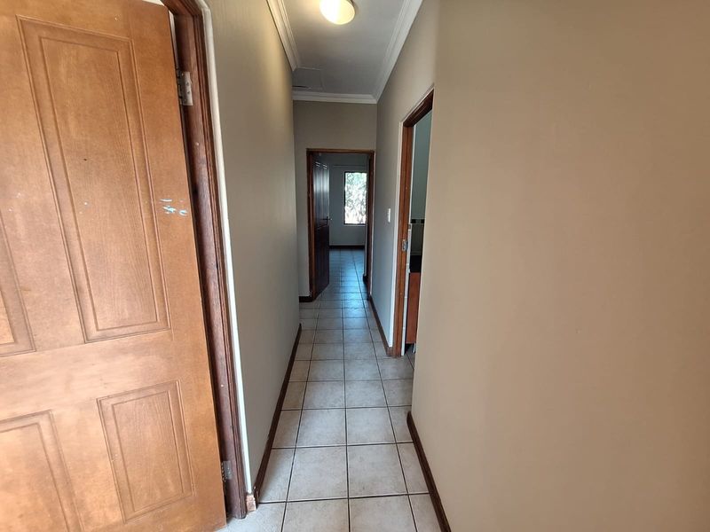 A functional hallway featuring tiled flooring, neutral wall paint, and access to multiple rooms within the townhouse.