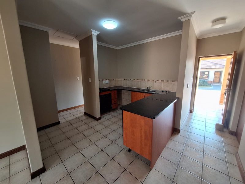 A functional kitchen featuring built-in cabinetry, granite countertops, a double sink, and tiled flooring, offering a clean and practical layout.
