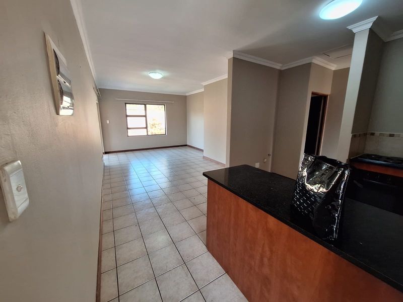 An open-plan living and kitchen area featuring tiled flooring, granite countertops, and neutral wall finishes, offering a versatile space for dining and relaxation.