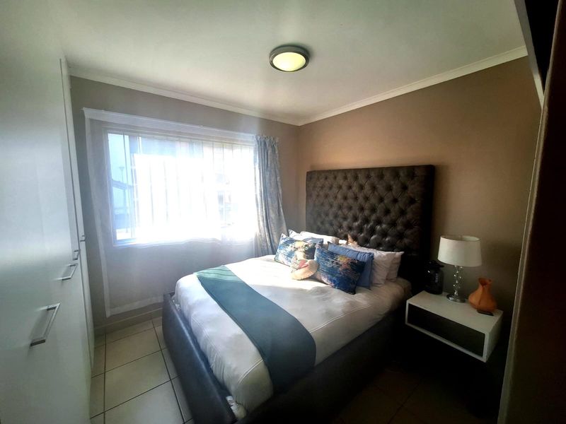 A well-maintained bedroom featuring built-in cupboards, tiled flooring, and a neutral color scheme, providing a comfortable and functional living space.