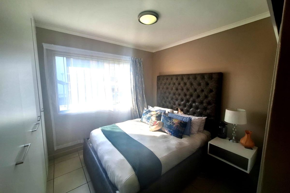 A well-maintained bedroom featuring built-in cupboards, tiled flooring, and a neutral color scheme, providing a comfortable and functional living space.