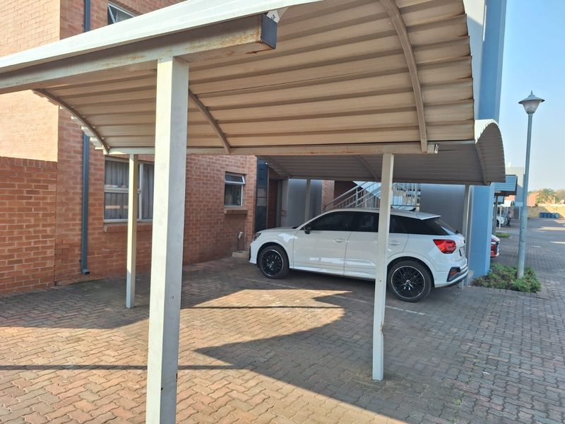 Covered carport parking area with brick paving and brick building exterior.