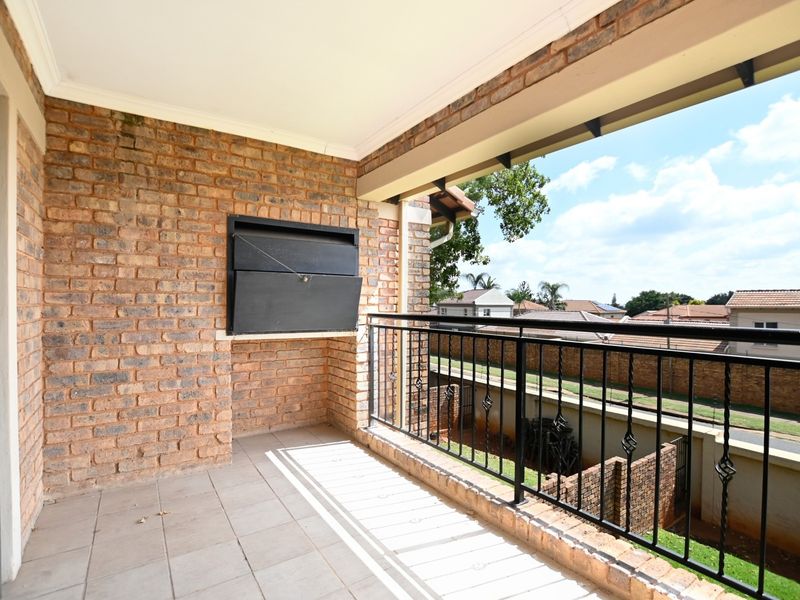 Covered balcony featuring a built-in braai, brick wall finish, and metal balustrade, offering an outdoor space suitable for entertaining.