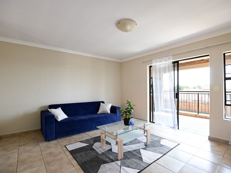 A bright living room featuring tiled flooring and a sliding glass door providing direct access to an outdoor balcony area.