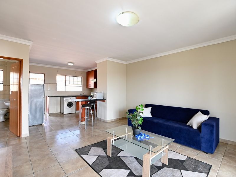 Open plan living area featuring tiled floors, a functional kitchen with breakfast bar, and direct access to an adjacent bathroom.