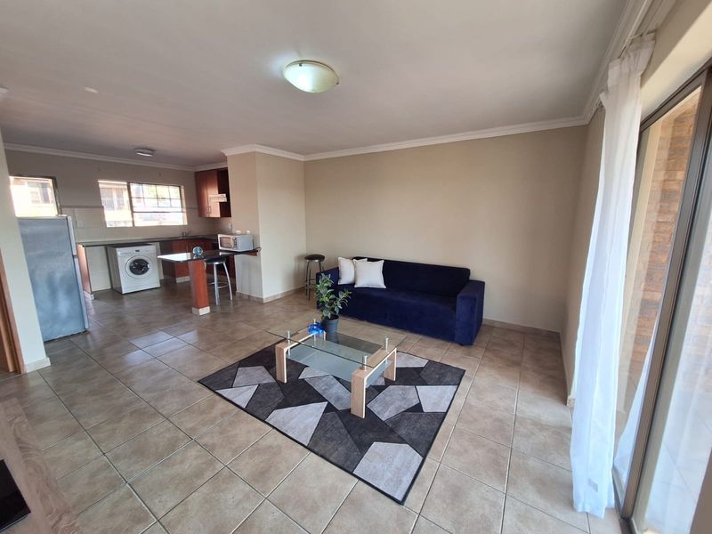 Open-plan living area featuring tiled floors, a functional kitchen with breakfast bar, and sliding door access to the exterior.