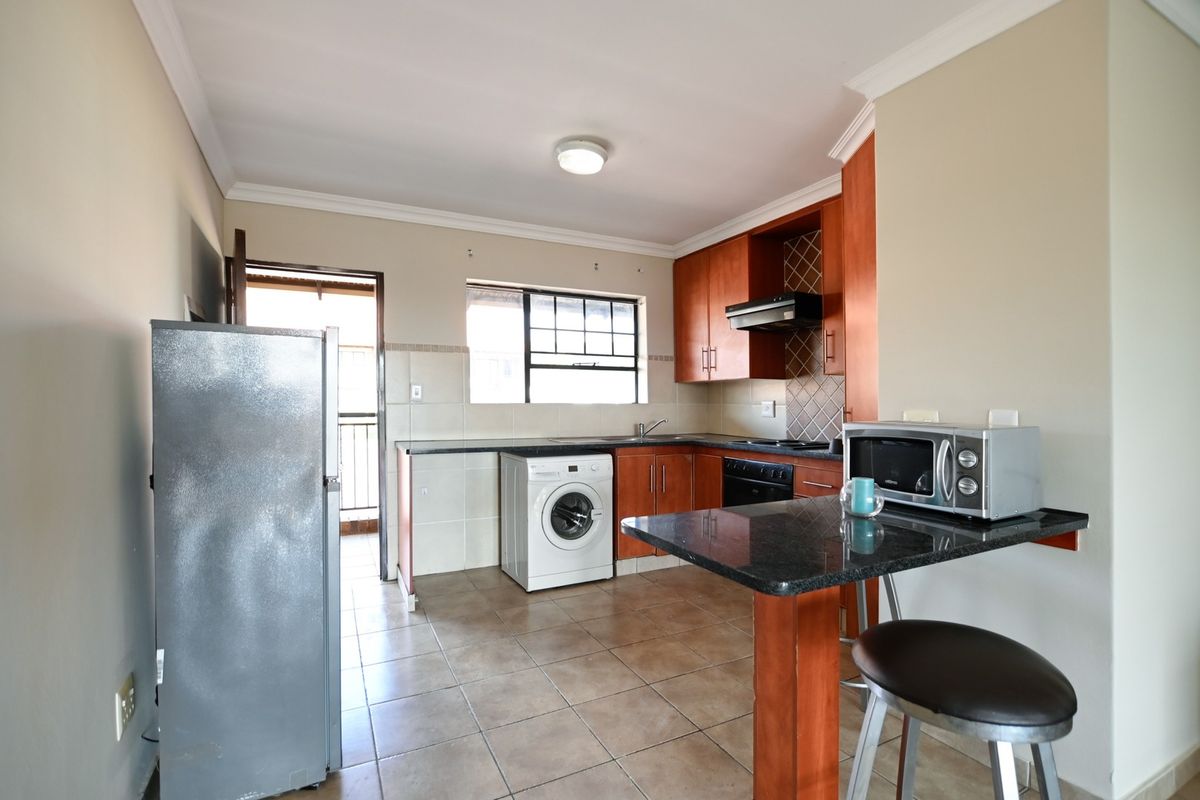 Functional kitchen featuring granite countertops, built-in wooden cabinetry, integrated appliances, and a convenient breakfast nook, with direct access to an outdoor area.