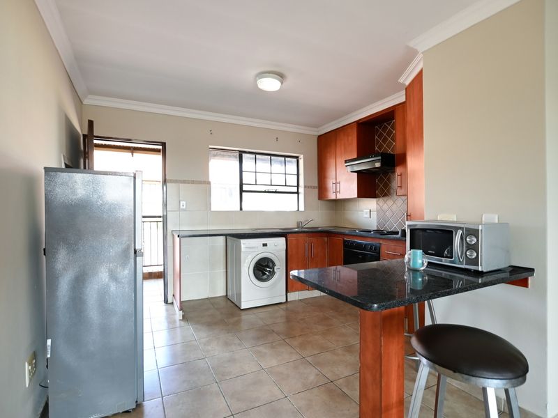Functional kitchen featuring granite countertops, built-in wooden cabinetry, integrated appliances, and a convenient breakfast nook, with direct access to an outdoor area.