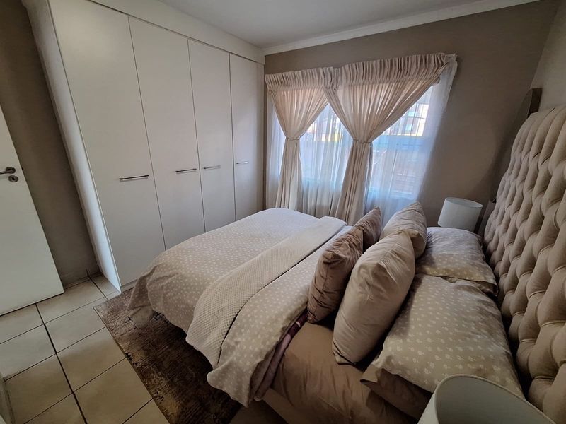 A well-maintained bedroom featuring neutral tones, tiled flooring, and ample built-in wardrobe storage space.