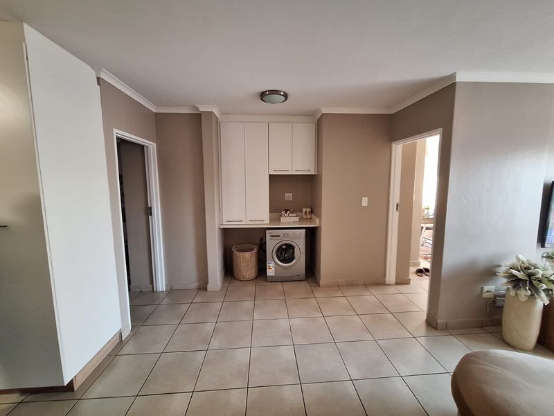 A functional laundry area featuring built-in white cabinetry, tiled flooring, and a dedicated space for a washing machine.
