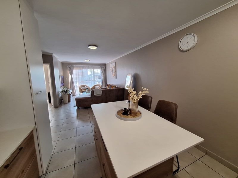 An open-plan living and dining area featuring tiled flooring, a central kitchen island, and a sliding glass door leading to an outdoor space.