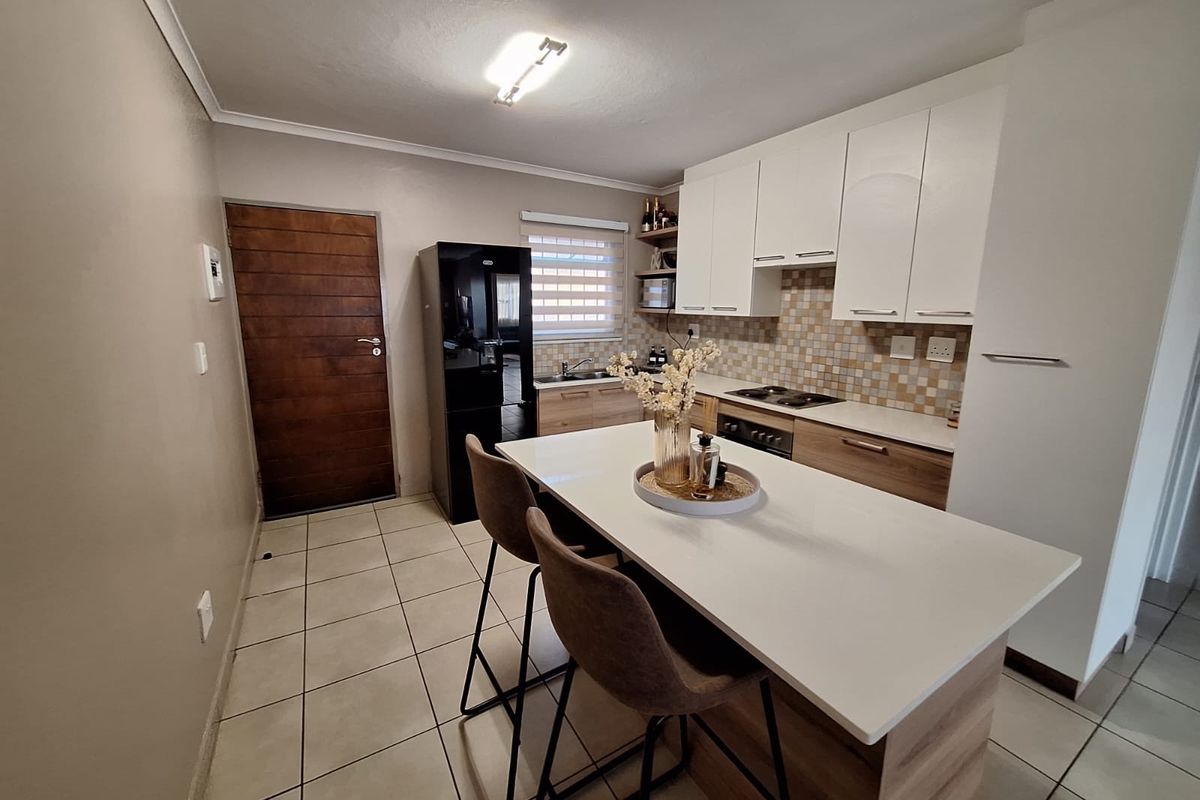 Modern kitchen featuring white and timber cabinetry, stone countertops, a central island, mosaic backsplash, and tiled flooring.