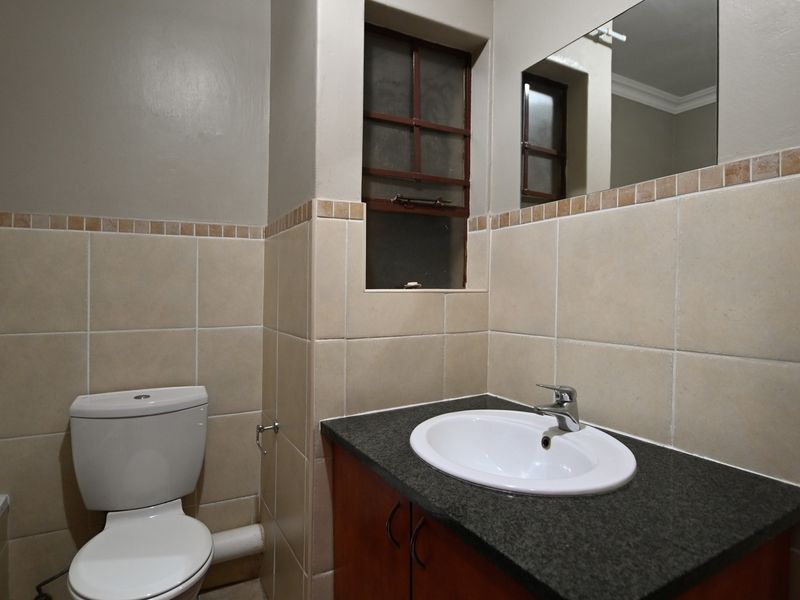 A functional bathroom featuring a vanity with granite countertop, drop-in basin, wall mirror, and tiled finishes.