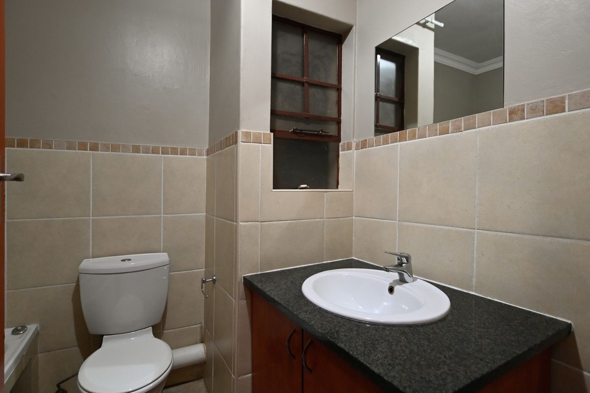 A functional bathroom featuring a vanity with granite countertop, drop-in basin, wall mirror, and tiled finishes.