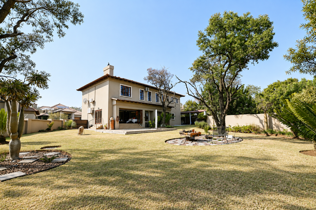 Spacious rear garden featuring a well-maintained lawn, mature trees, a paved fire pit area, and a view of the two-story residential building.