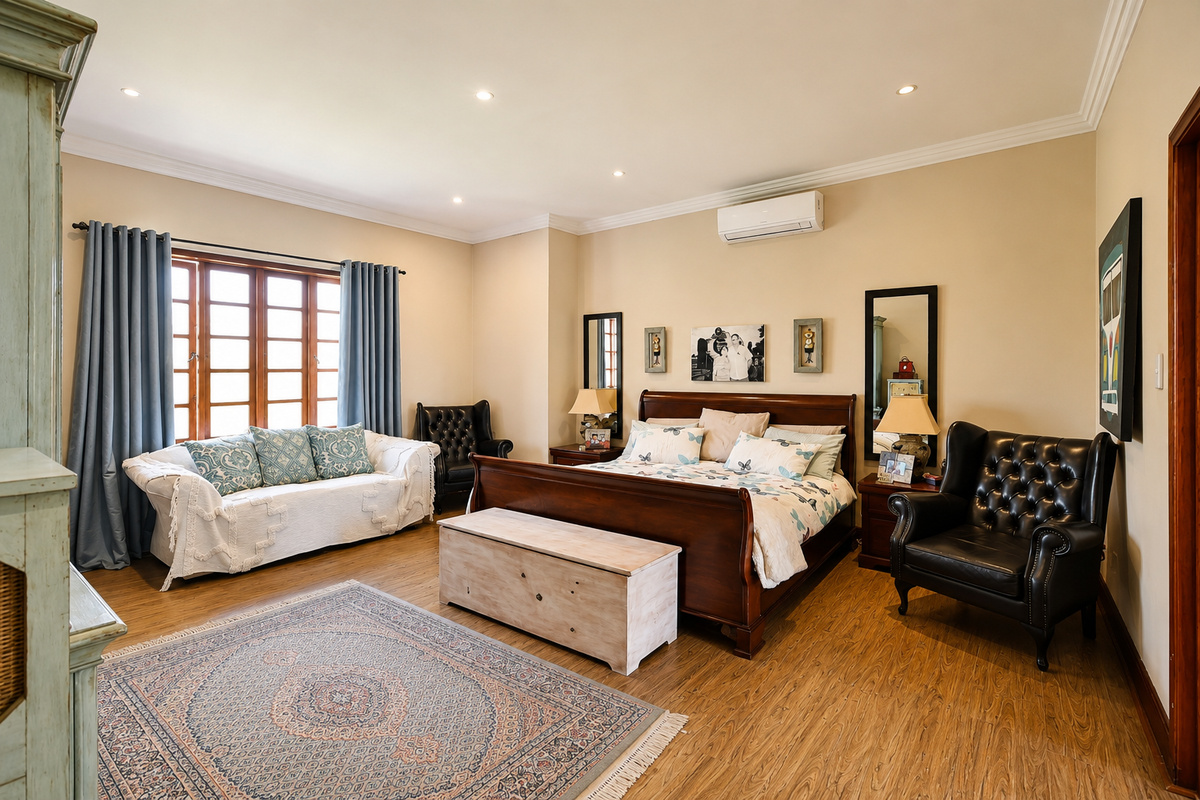 A spacious bedroom featuring timber laminate flooring, recessed downlighting, and a wall-mounted split-system air conditioning unit, with large timber-framed windows.