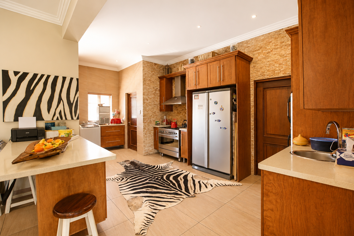 Spacious kitchen featuring warm wooden cabinetry, stone veneer wall accents, quartz countertops, and integrated stainless steel appliances with recessed lighting.
