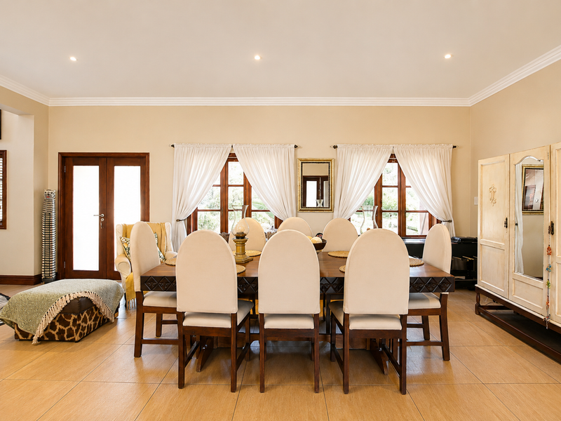 A spacious dining room featuring large format floor tiles, crown molding, recessed lighting, and timber-framed windows and doors providing natural light.