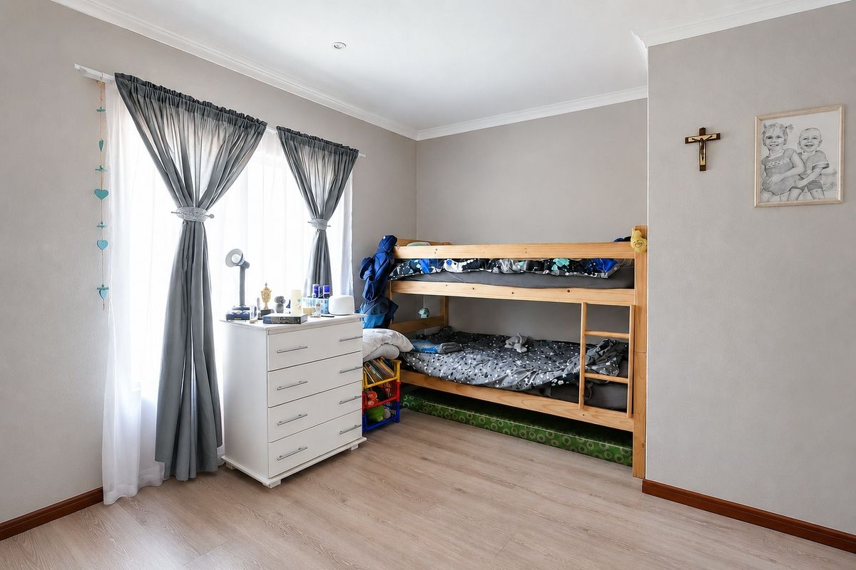 A well-maintained bedroom featuring light-toned laminate flooring, neutral wall finishes, and a recessed downlight.