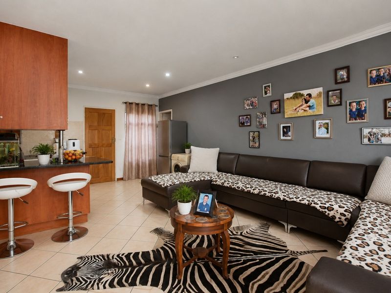 Open plan living area featuring tiled flooring, recessed lighting, and a kitchen breakfast bar with granite countertops.