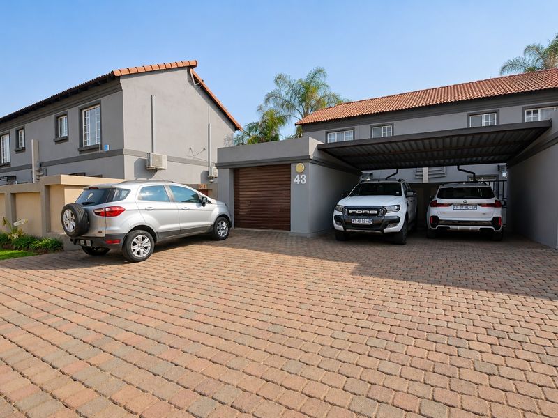 Front exterior view of a townhouse featuring a paved driveway, a covered carport, and a single garage.
