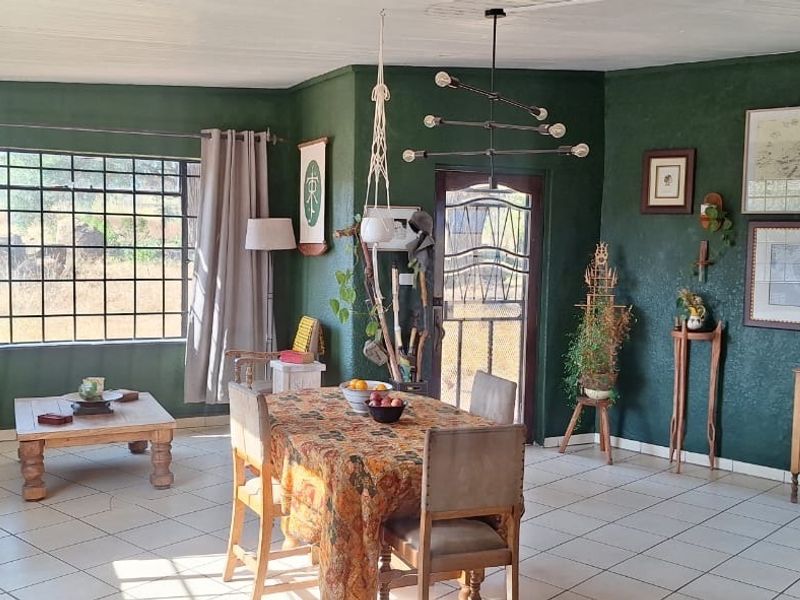 A living area featuring tiled flooring, grid-pattern windows, and a security gate, finished with dark green walls and a modern chandelier.