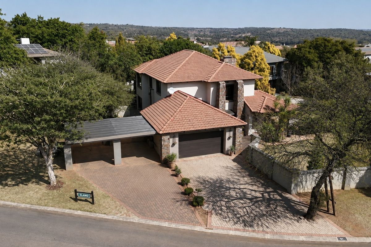 Aerial view of a double-story residential property featuring a tiled roof, paved driveway, double garage, and an attached carport.