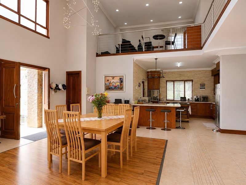 Spacious open-plan living and dining area featuring a double-volume ceiling, mezzanine level, and a well-appointed kitchen with a central island.