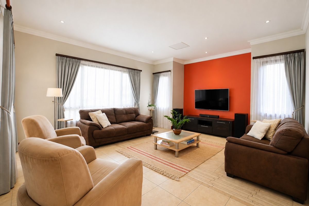 A well-maintained living room featuring tiled flooring, recessed downlighting, and a prominent feature wall, offering a comfortable and bright living space.