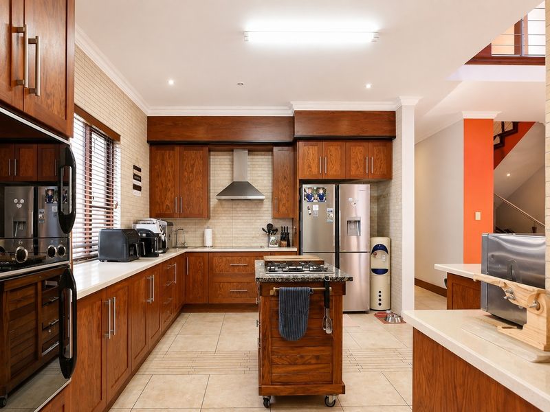 A well-maintained kitchen featuring warm wooden cabinetry, granite countertops, a central island, and integrated stainless steel appliances with a tiled backsplash.
