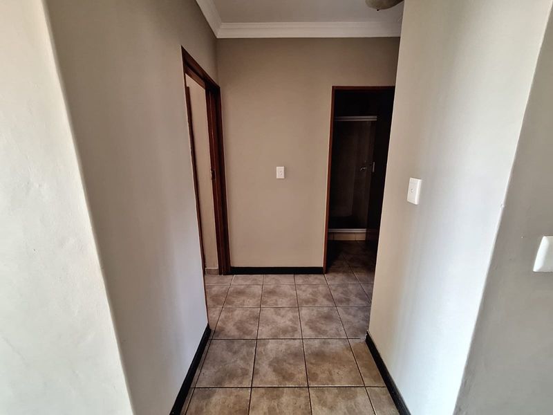 A clean, neutral-toned hallway featuring tiled flooring and access to adjacent rooms, providing a functional transition space within the townhouse.
