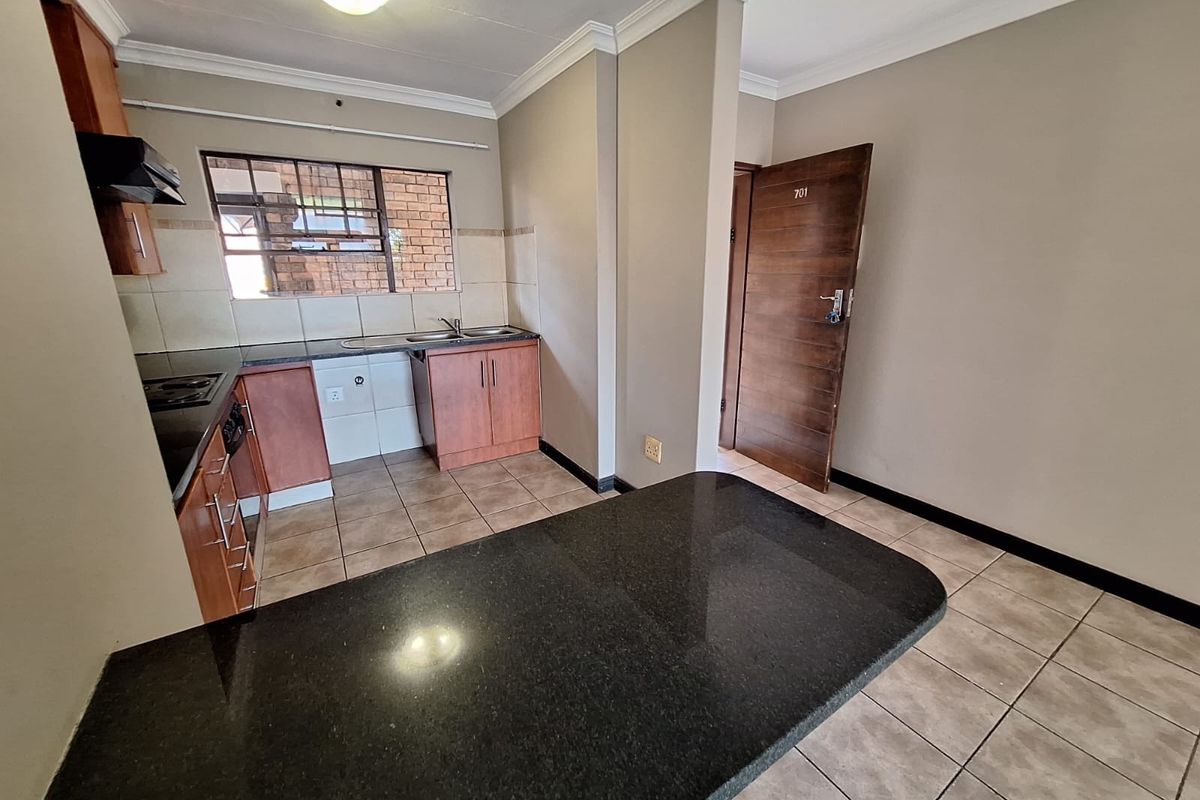 A functional kitchen featuring granite countertops, built-in cabinetry, and tiled flooring, offering a clean and practical space for culinary activities.