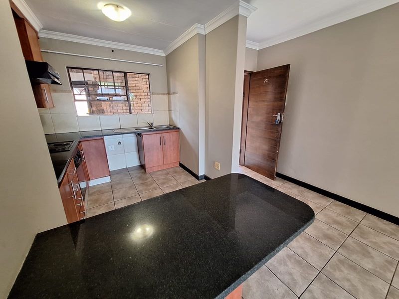 A functional kitchen featuring granite countertops, built-in cabinetry, and tiled flooring, offering a clean and practical space for culinary activities.